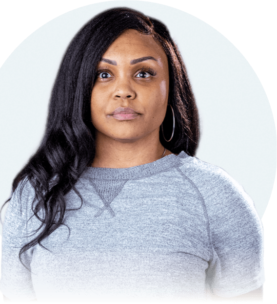 An African-American woman with long brown hair is seen from the waist up. She is looking straight at the camera