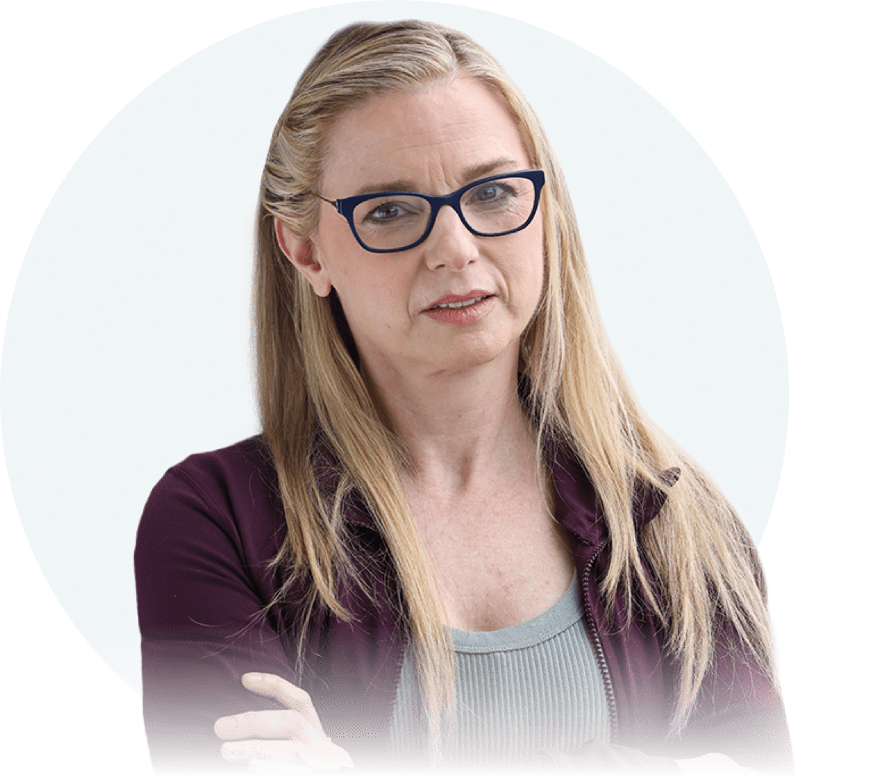 A white woman with long blonde hair and dark glasses is seen from the chest up. She is facing the camera with a concerned expression