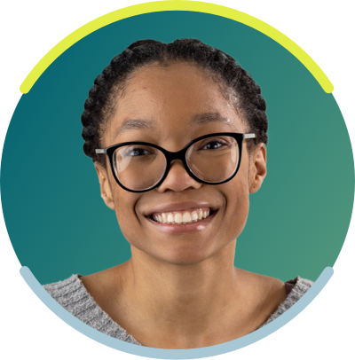 Young African American woman with her braided, she is seen from the neck up. She has dark glasses on and is smiling.